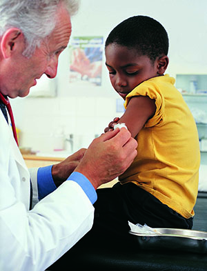 Doctor is preparing to give a boy a shot in the arm